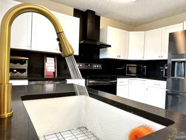 kitchen featuring wall chimney exhaust hood, white cabinetry, a textured ceiling, stainless steel appliances, and backsplash