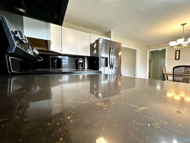 kitchen with a textured ceiling, a notable chandelier, white cabinetry, stainless steel fridge with ice dispenser, and decorative light fixtures