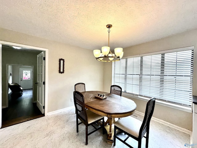 dining room with a textured ceiling, baseboards, and a notable chandelier