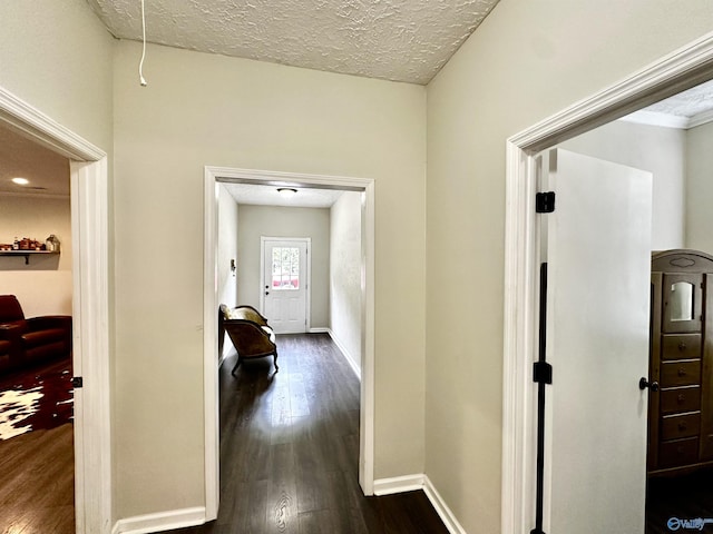 hall featuring dark wood-style floors, a textured ceiling, and baseboards