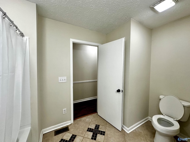 bathroom featuring tile patterned floors, toilet, a shower with shower curtain, and a textured ceiling