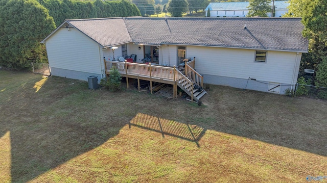 rear view of property featuring a yard, a shingled roof, a wooden deck, and fence