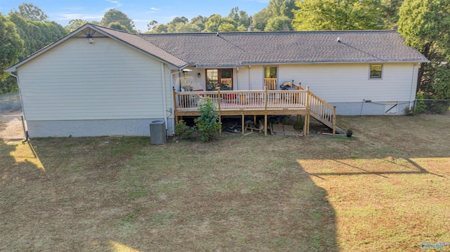 back of house featuring roof with shingles, a lawn, and a deck