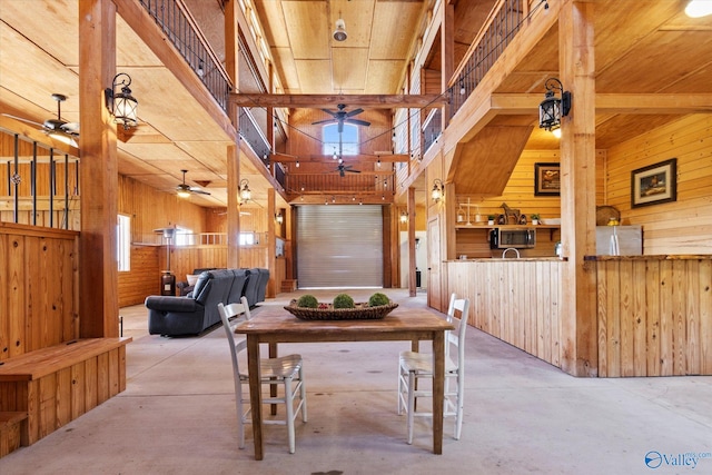 interior space with wooden walls, concrete flooring, a high ceiling, and plenty of natural light