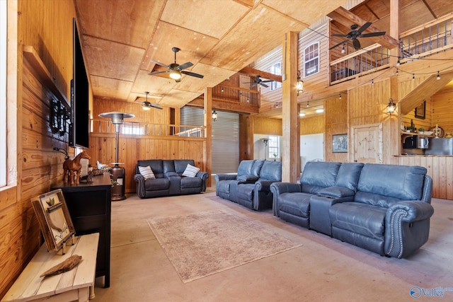 living room featuring wood walls, concrete flooring, and a high ceiling