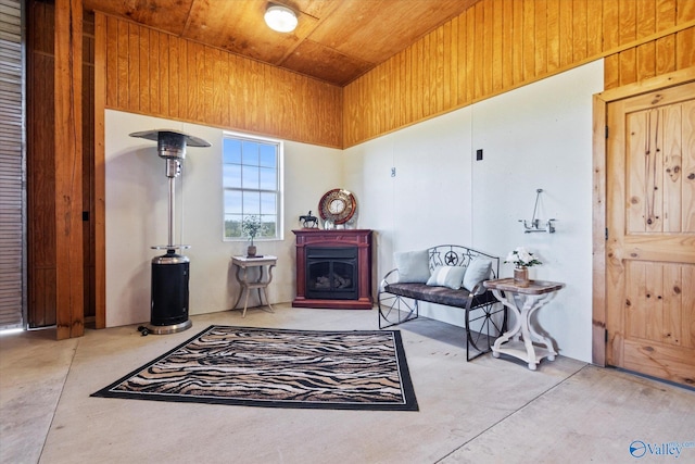 living area featuring wood walls, a high ceiling, and concrete flooring