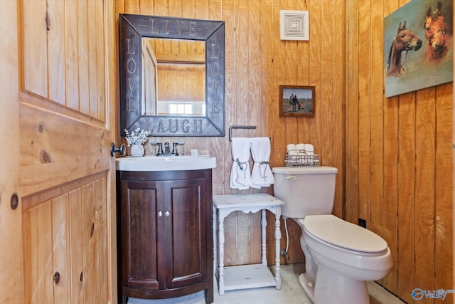 bathroom with vanity, toilet, and wooden walls