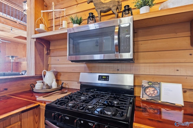 kitchen with gas stove and wood walls