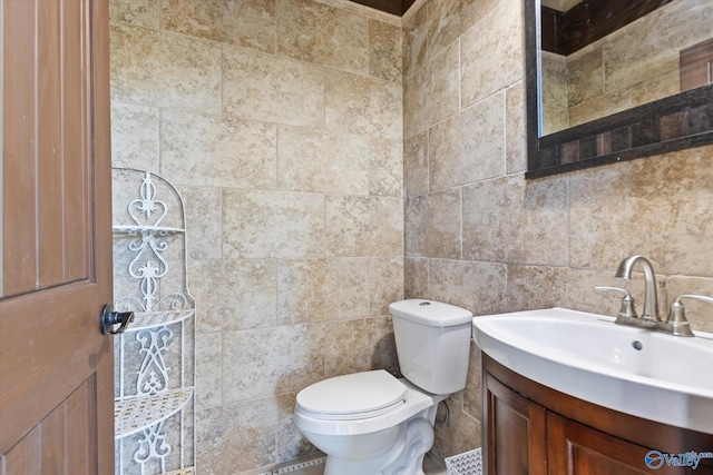 bathroom with vanity, toilet, and tile walls