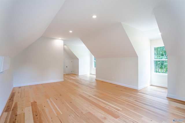 additional living space featuring vaulted ceiling and light hardwood / wood-style flooring