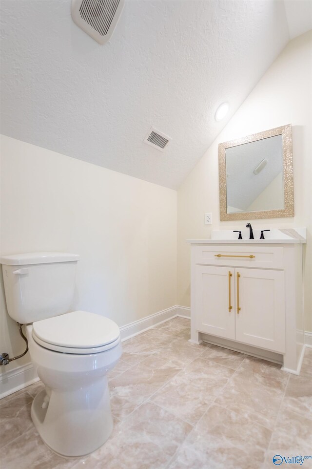 bathroom featuring vanity, a textured ceiling, toilet, lofted ceiling, and tile patterned flooring