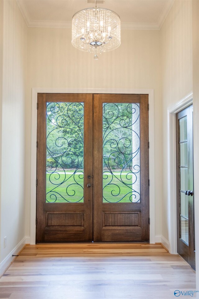 foyer featuring a notable chandelier, french doors, light hardwood / wood-style flooring, and ornamental molding