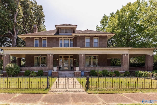 traditional style home with a gate, a porch, a front lawn, a fenced front yard, and brick siding