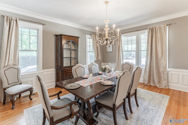 dining area featuring a wainscoted wall, light wood-style floors, a chandelier, and ornamental molding