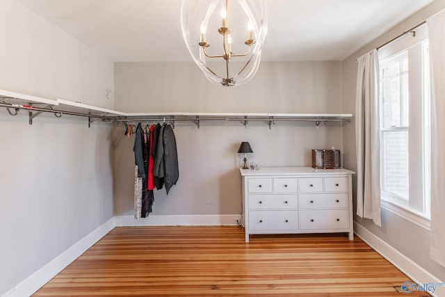 walk in closet with light wood-type flooring and a notable chandelier