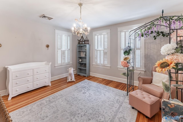 living area with a wealth of natural light, light hardwood / wood-style flooring, and a chandelier