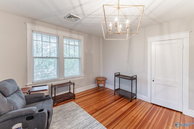 living area featuring light wood-type flooring, visible vents, baseboards, and a notable chandelier