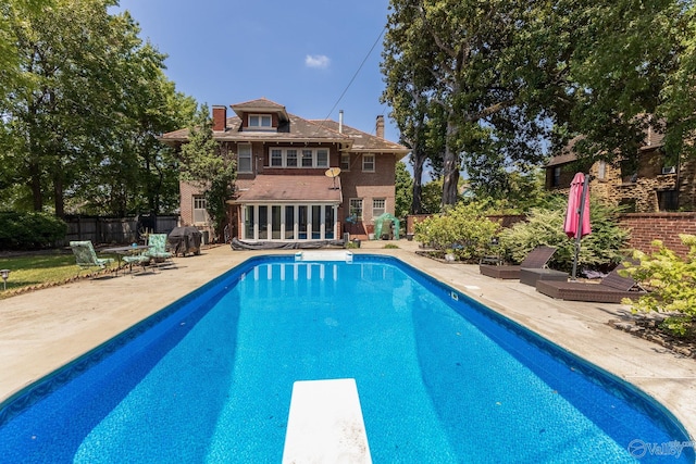 view of pool with a diving board and a patio area