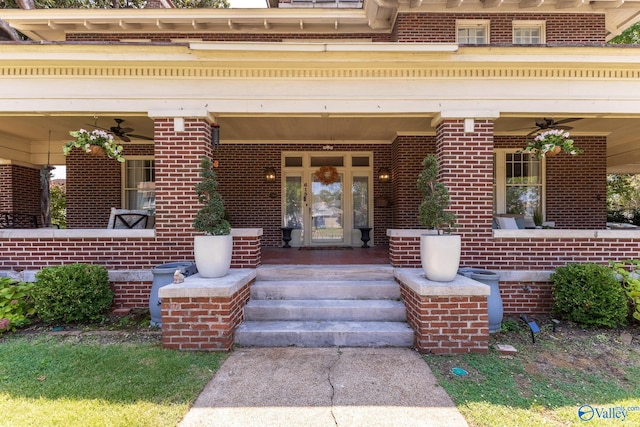 view of exterior entry featuring brick siding, a ceiling fan, and covered porch