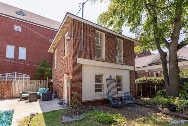 back of property featuring fence, brick siding, outdoor lounge area, and a patio area