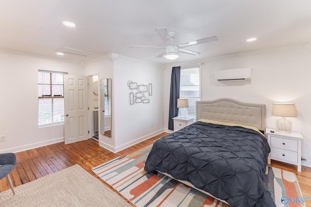 bedroom featuring ceiling fan, crown molding, light hardwood / wood-style flooring, and a wall unit AC