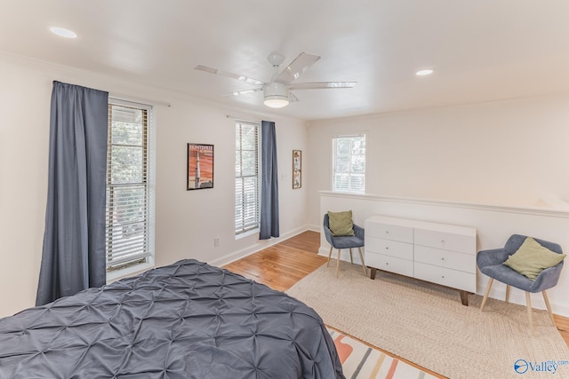 bedroom featuring ceiling fan, light hardwood / wood-style flooring, and multiple windows