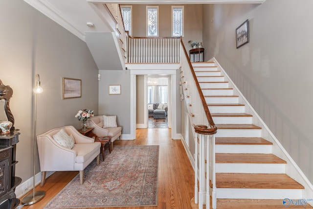 staircase featuring a high ceiling, baseboards, and wood finished floors