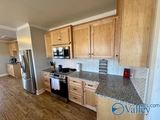 kitchen featuring dark wood-type flooring, light brown cabinets, ornamental molding, appliances with stainless steel finishes, and dark stone counters