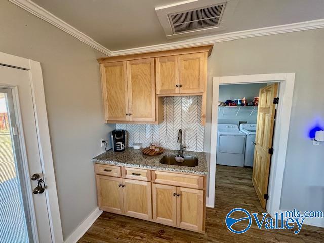 kitchen featuring independent washer and dryer, ornamental molding, dark hardwood / wood-style flooring, and sink