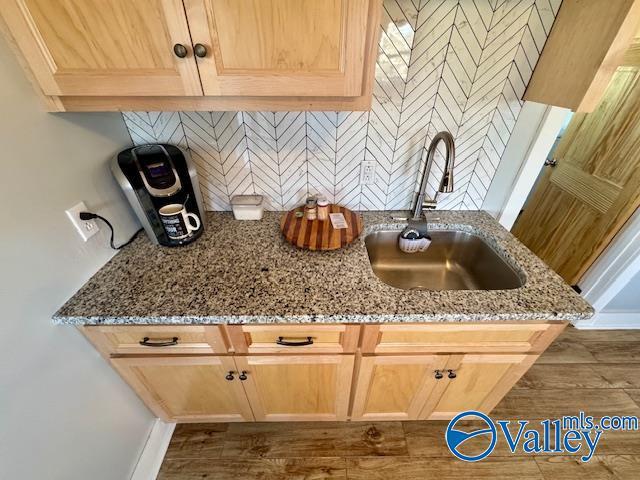 room details with light brown cabinetry, tasteful backsplash, sink, dark hardwood / wood-style flooring, and light stone counters