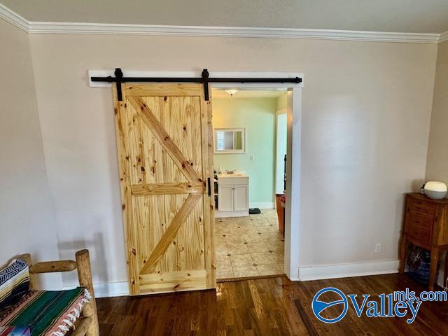 interior space with hardwood / wood-style flooring, ornamental molding, and a barn door