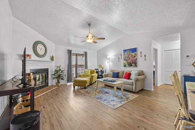 living room featuring lofted ceiling, a textured ceiling, ceiling fan, and light wood-type flooring