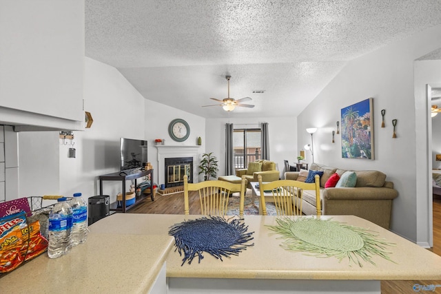 living room featuring ceiling fan, lofted ceiling, hardwood / wood-style floors, and a textured ceiling