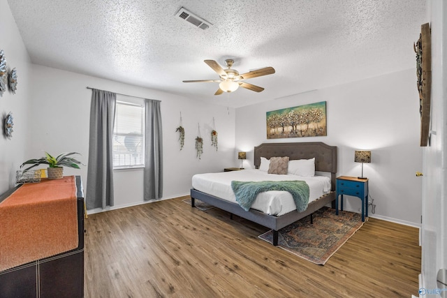 bedroom with hardwood / wood-style flooring, ceiling fan, and a textured ceiling