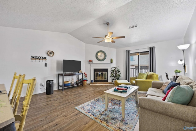 living room with dark hardwood / wood-style flooring, a textured ceiling, vaulted ceiling, and ceiling fan