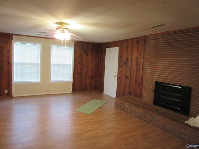 3201 Holmes Ave, Huntsville, AL 35816 - unfurnished living room with a fireplace, a ceiling fan, wood finished floors, and wooden walls