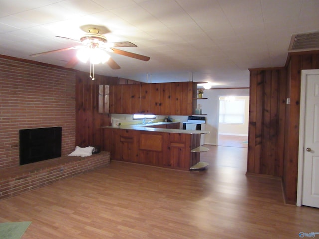 3201 Holmes Ave, Huntsville, AL 35816 - kitchen with a peninsula, light wood-style flooring, wood walls, brown cabinetry, and a ceiling fan