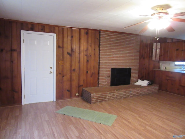 3201 Holmes Ave, Huntsville, AL 35816 - unfurnished living room with a ceiling fan, wood finished floors, wooden walls, and a brick fireplace