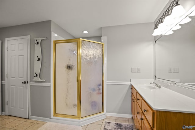 bathroom with a shower with door, vanity, and tile patterned floors