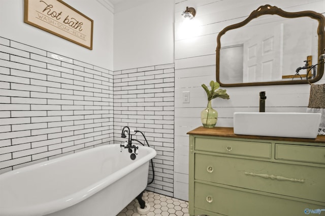 bathroom featuring tile walls, tile patterned flooring, vanity, a washtub, and crown molding