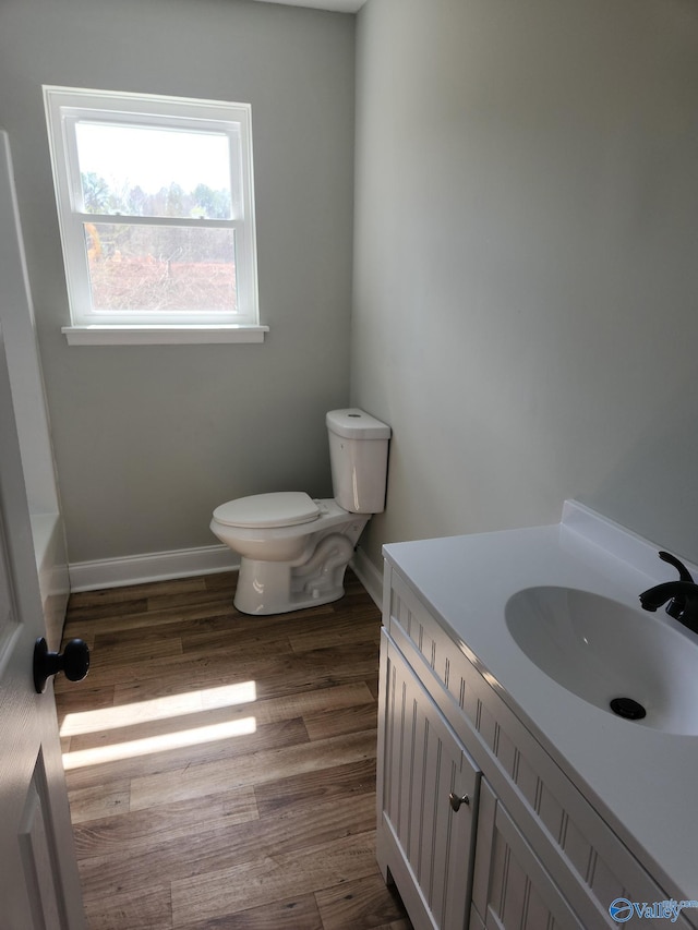 bathroom featuring toilet, vanity, baseboards, and wood finished floors