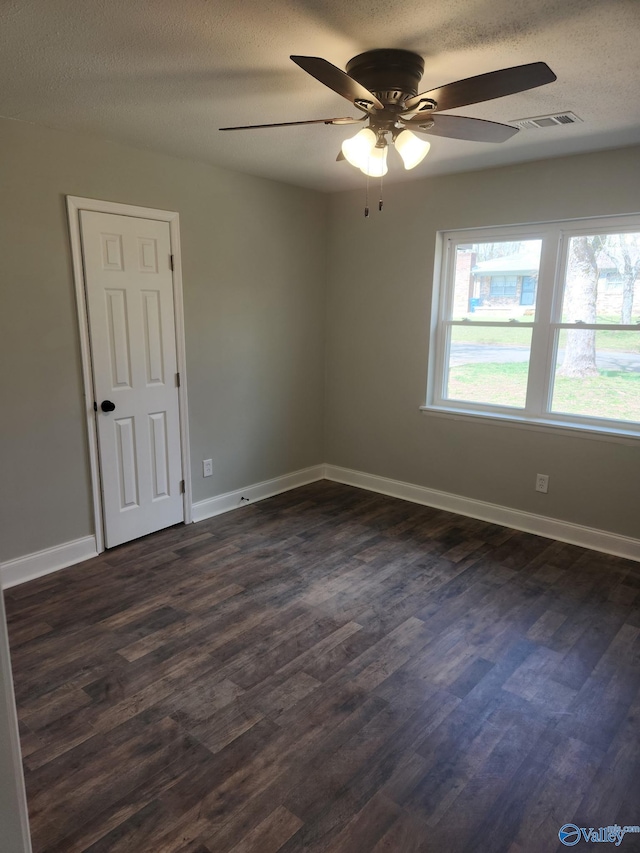 unfurnished room featuring visible vents, baseboards, dark wood finished floors, a textured ceiling, and a ceiling fan