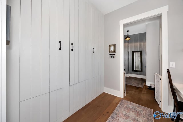 corridor featuring baseboards and wood finished floors