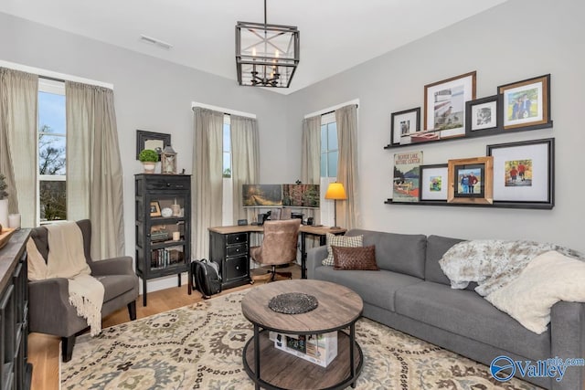 living room featuring visible vents, an inviting chandelier, and wood finished floors