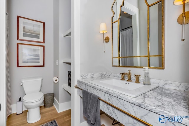 full bath with baseboards, toilet, wood finished floors, and vanity