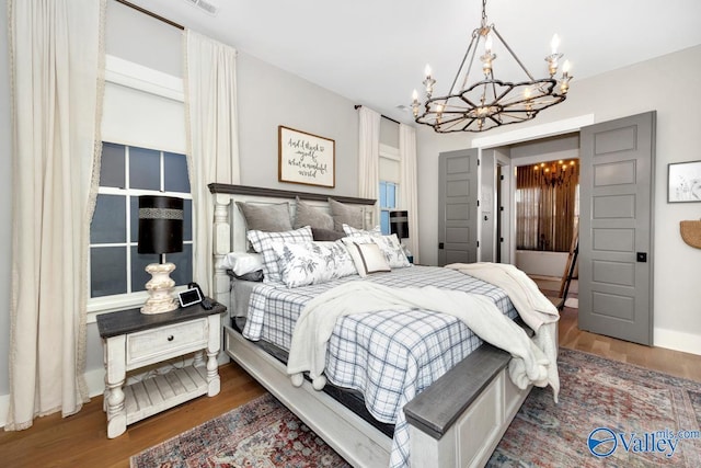 bedroom featuring wood finished floors, visible vents, and a chandelier