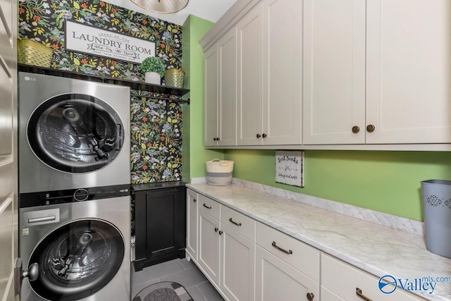 laundry area with cabinet space, stacked washer and clothes dryer, and tile patterned flooring