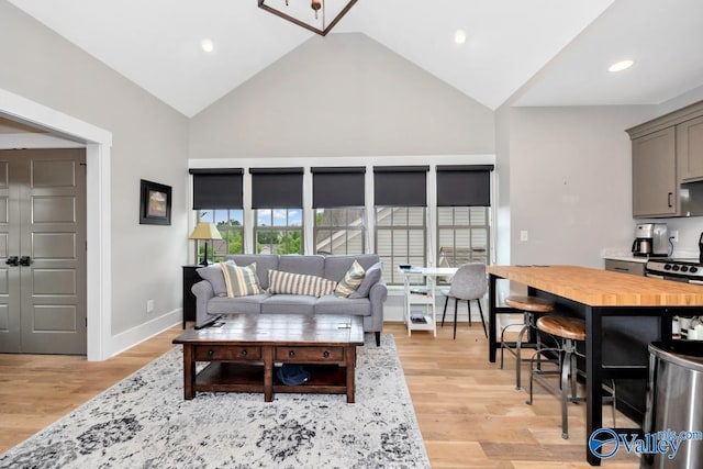 living area featuring recessed lighting, light wood-type flooring, baseboards, and high vaulted ceiling