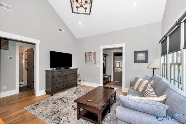 living room with visible vents, baseboards, high vaulted ceiling, and light wood finished floors