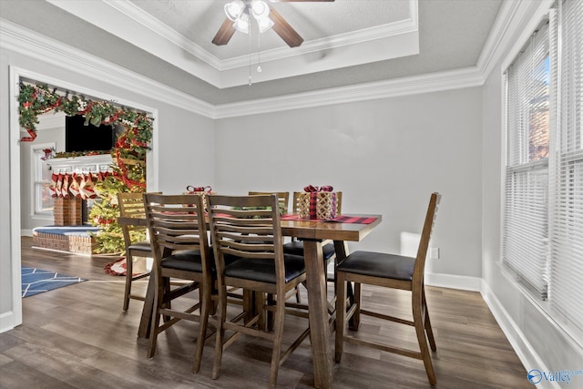 dining room with ceiling fan, ornamental molding, dark wood-type flooring, and a tray ceiling